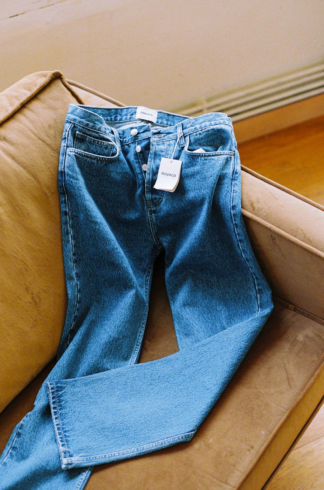 jean bleu coupe droite posé sur le bord d'un canapé en cuir marron