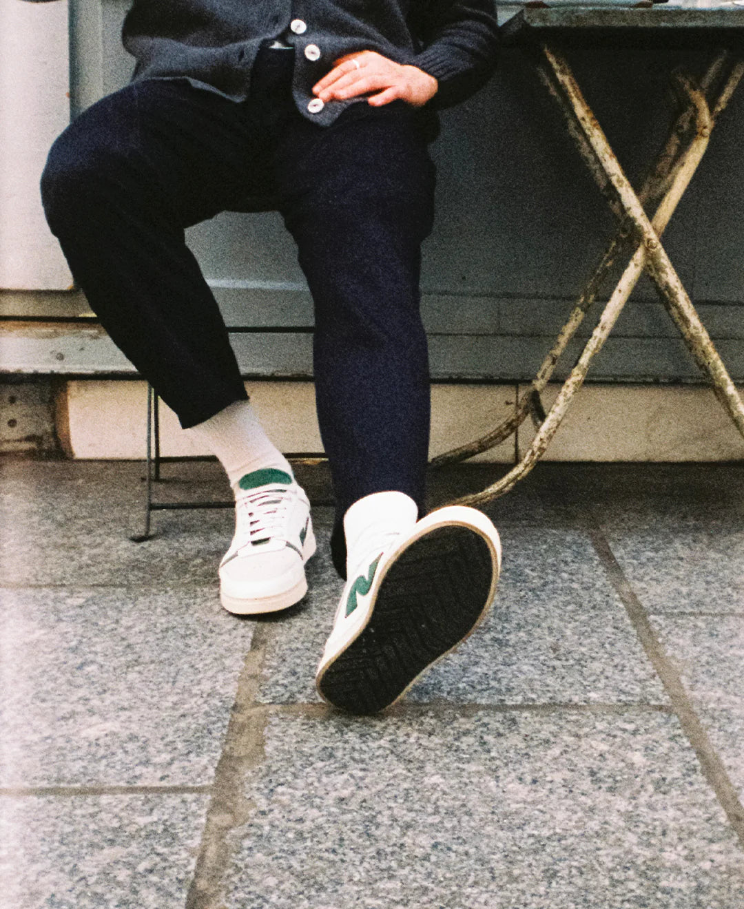 homme assis à une table, les jambes croisées portant des chaussures blanches noyoco