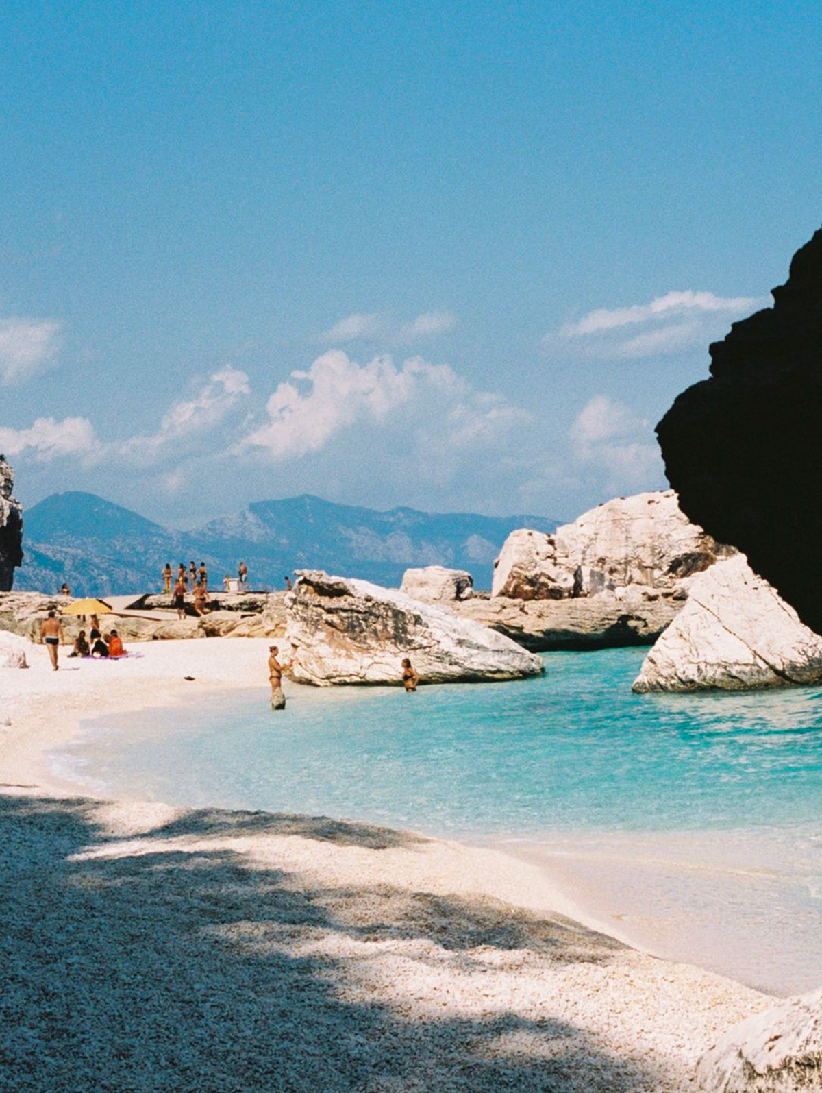 lagon bleu entre une plage de sable fin blanc et des rochers blancs