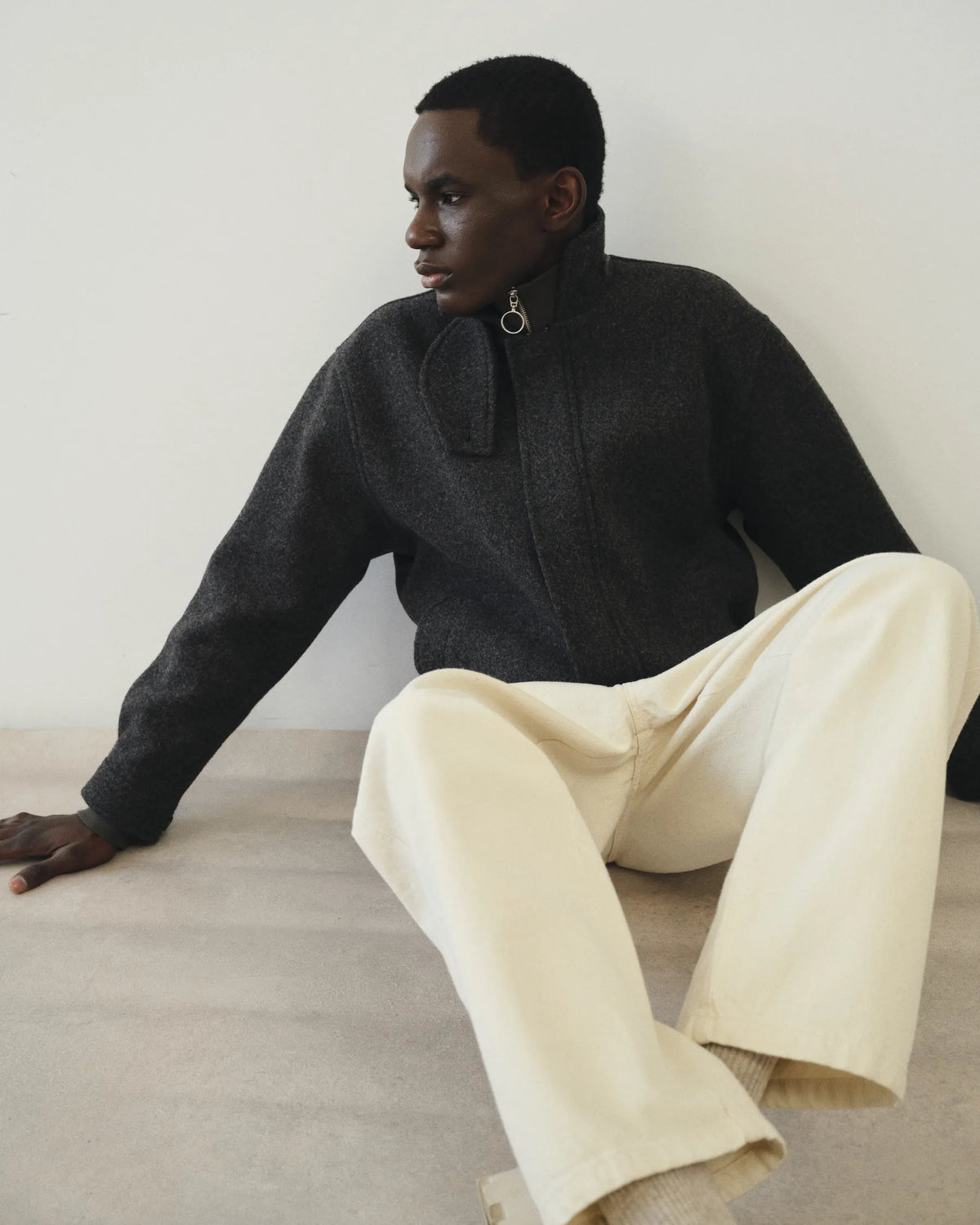 Silhouette homme assise en maille anthracite et pantalon écru