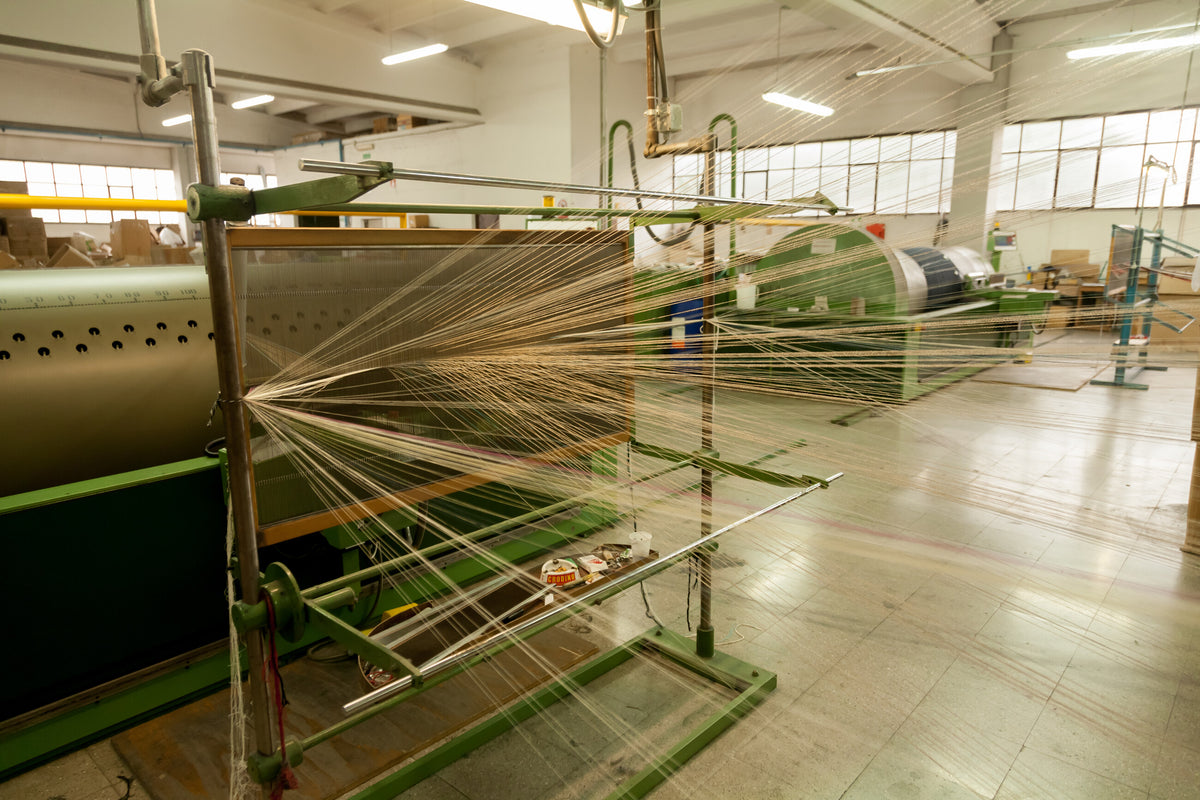 Fils de chaîne traversant une machine de tissage dans l’atelier Zanieri à Prato