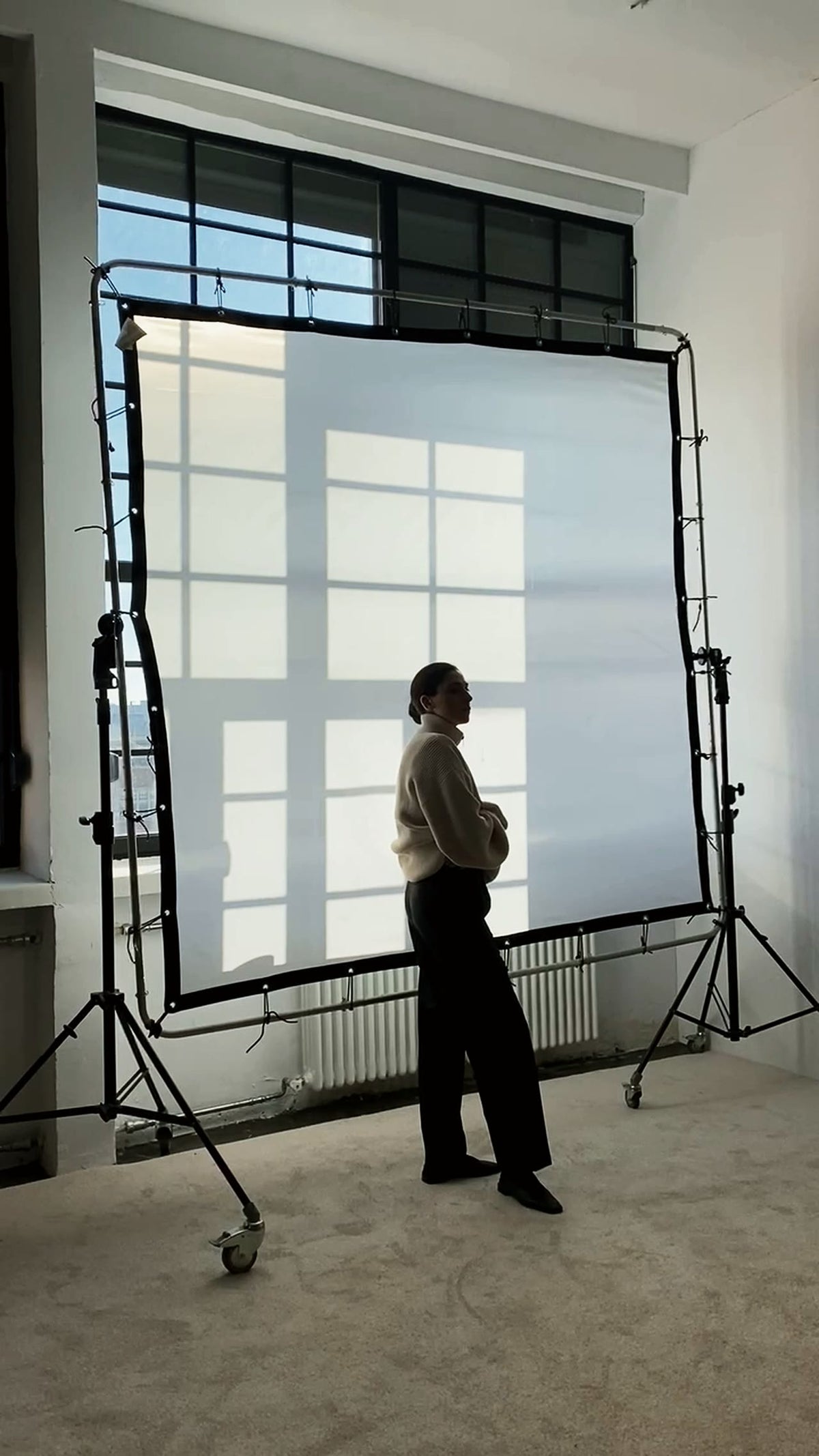 Silhouette devant un fond de studio traversé par la lumière.